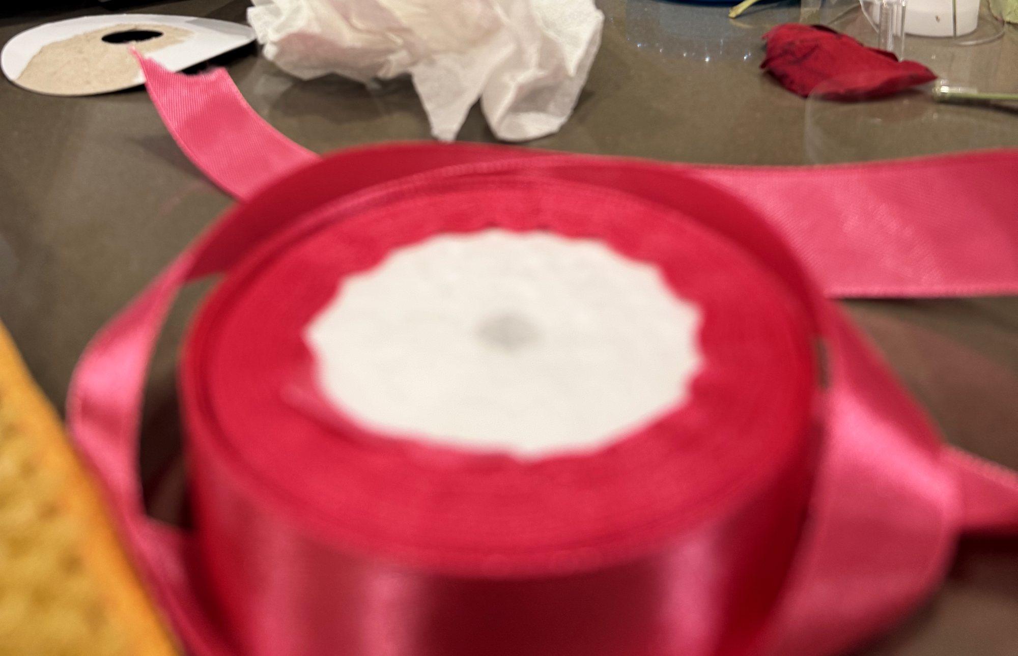 A spool of red satin ribbon on the worktable