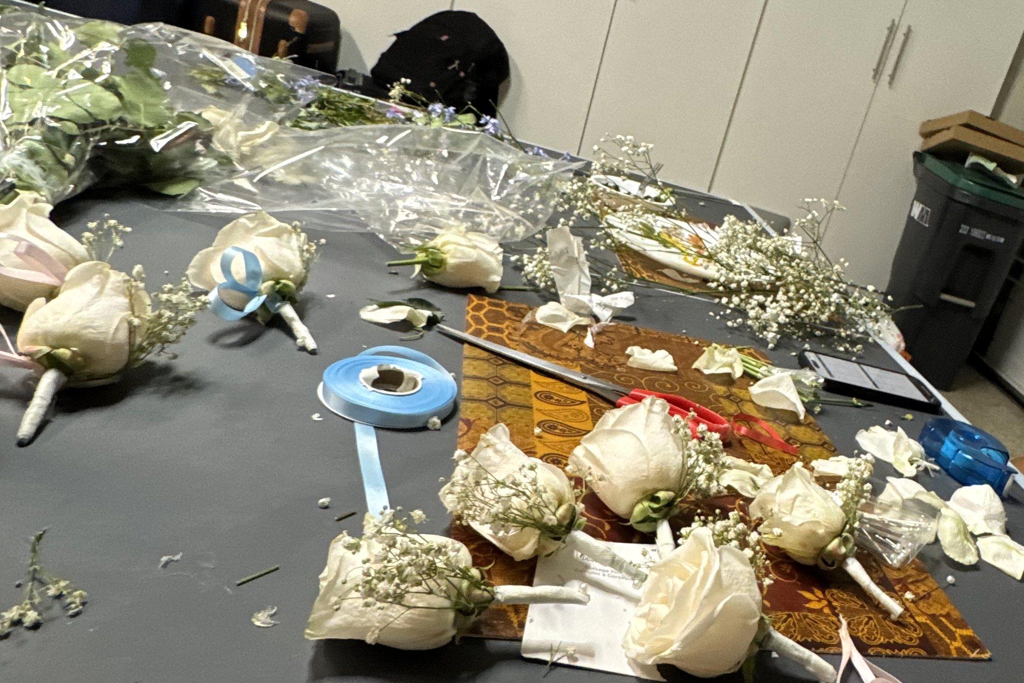 White rose boutonnières being finished on a worktable